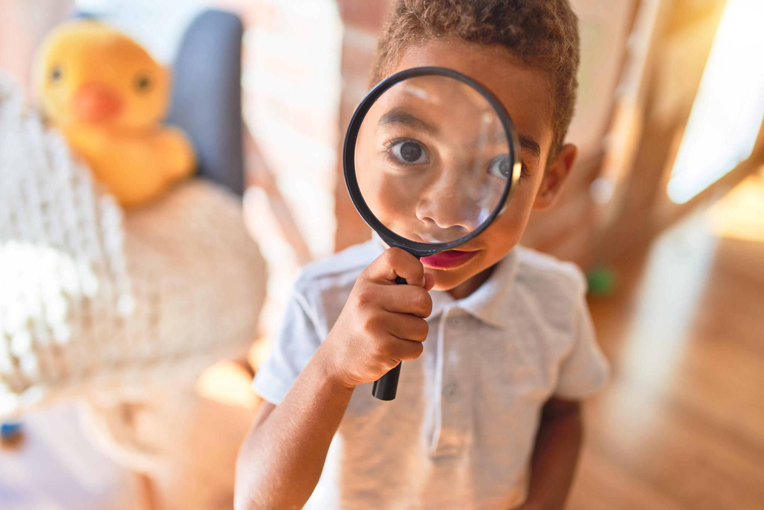 Young boy holding magnifying glass up in front of his face