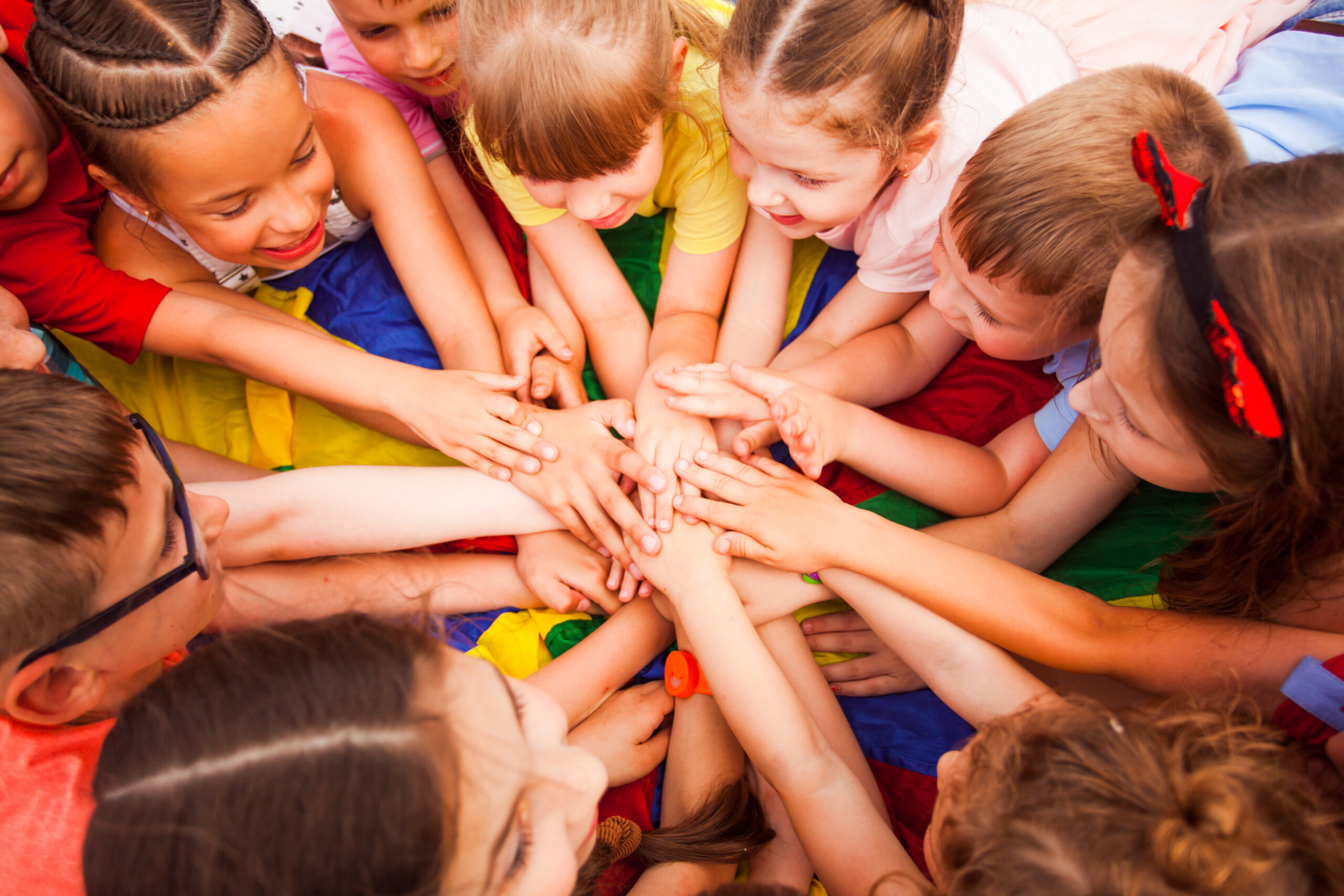 Children circled around each other putting hands on top of each others 