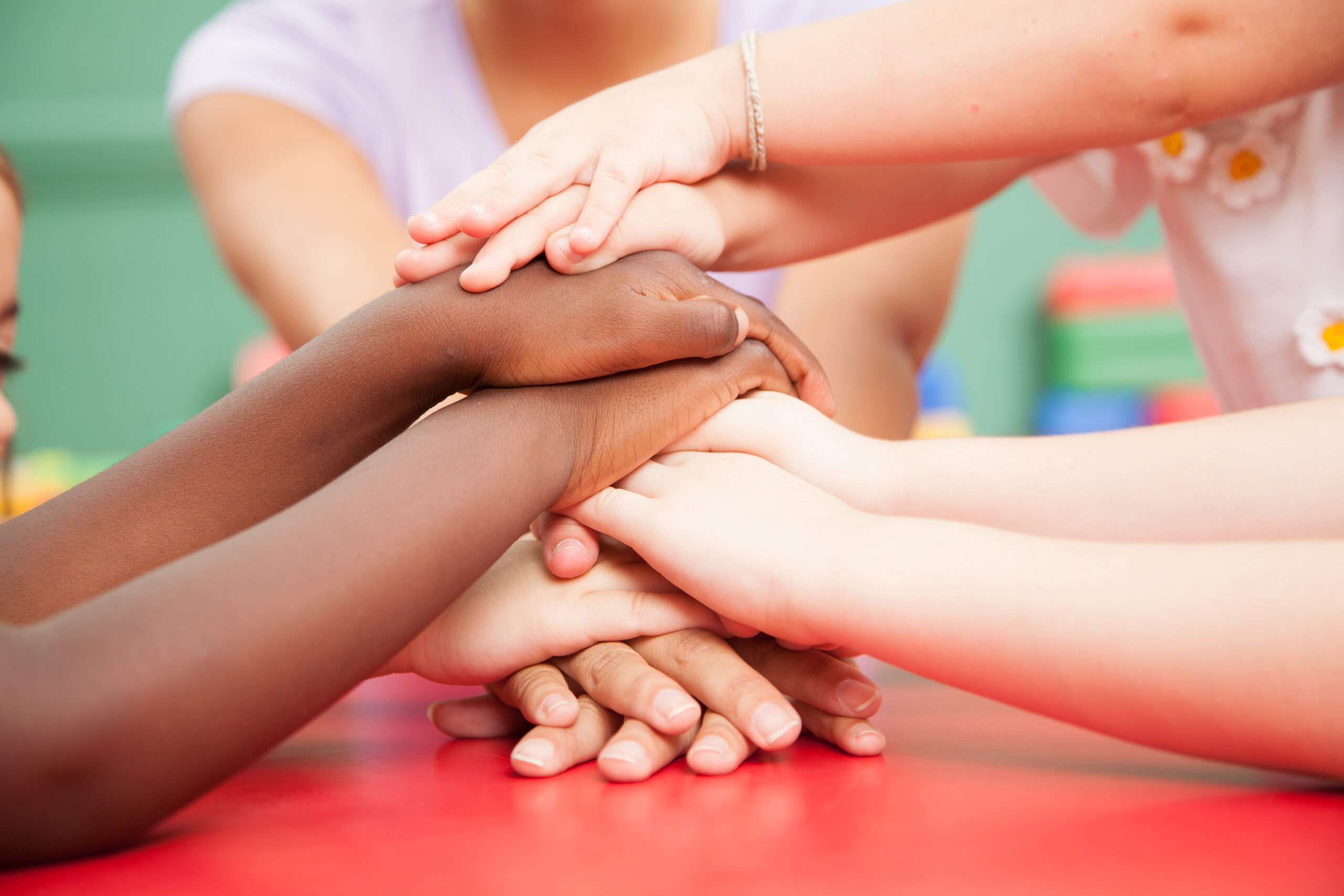 Children with hands together on top of table